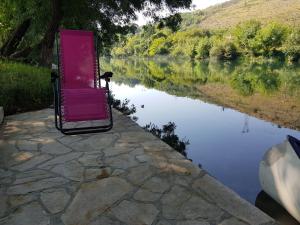 ein rosa Stuhl neben einem Gewässer in der Unterkunft Villa Buna in Buna