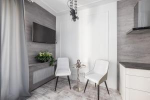 cocina con 2 sillas y TV en la pared en Good Time Apartment Woronicza Warszawa, en Varsovia
