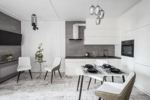 a white kitchen with a white table and chairs at Good Time Apartment Business Center in Warsaw