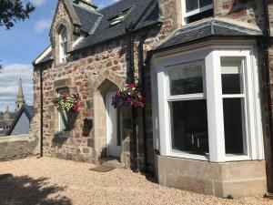uma casa de tijolos com janelas brancas e flores nela em View Cottage em Inverness