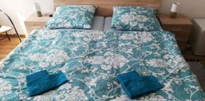 ein Bett mit blauer Bettdecke und zwei blauen Kissen in der Unterkunft Ubytování Schindler in Velké Poříčí