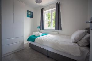 1 dormitorio con cama blanca y ventana en Kestrel House by RentMyHouse, en Hereford