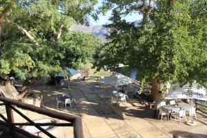 a patio with tables and chairs under some trees at Moholoholo Ya Mati in Kampersrus AH