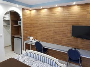 Zimmer mit einem Schreibtisch und einem TV an einer Holzwand in der Unterkunft L'Abribis in Firminy