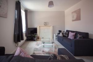 a living room with a blue couch and a table at Kestrel House by RentMyHouse in Hereford