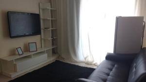 a living room with a couch and a flat screen tv at Flats no Quartier e Village Apart Hotel in Três Poços
