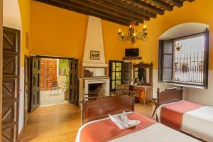 a bedroom with two beds and a fireplace at Hotel Posada de Don Rodrigo Antigua in Antigua Guatemala