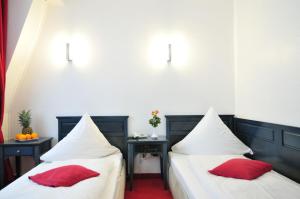 ケルンにあるセラノ シティ ホテル ケルン アム ドームの赤い枕が備わる客室内のベッド2台