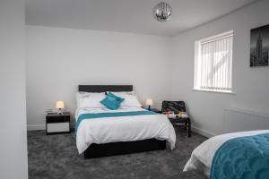 a white bedroom with a bed and a chair at Fantastic Large House with Private Parking in Bradford