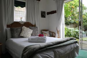 a bedroom with a bed with white sheets and a window at Forword's River Lodge in East London