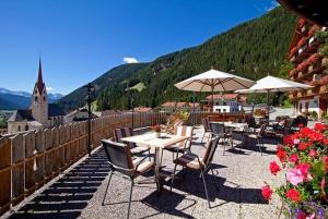 a group of tables and chairs with umbrellas on a patio at Hotel Hofmann in Santa Maddalena in Casies