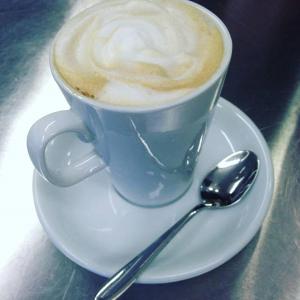 a cup of coffee on a plate with a spoon at Lynch's on the Pier in Castletownbere