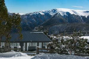 フォールズ・クリークにあるElk at Fallsの雪山を背景にした家
