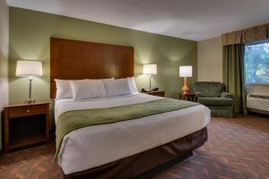 a hotel room with a large bed and a chair at Wingfield Inn & Suites in Elizabethtown