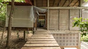 a wooden walkway leading to a building with a porch at La pajarera in Mazunte