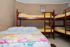 a room with three bunk beds and a brick wall at Pousada São Rafael in Cachoeira Paulista