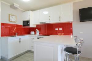 eine Küche mit weißen Schränken und roten Wänden in der Unterkunft Beachfront 2, 25 Willow Street in Crescent Head