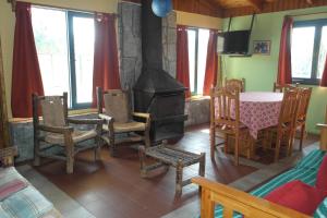 sala de estar con chimenea, mesa y sillas en Cabañas Los Tamarugos en Pichidangui