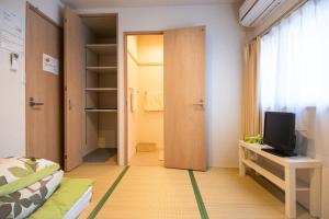 a bedroom with a door leading to a closet with a television at Osaka Guesthouse SAYURI TENGACHAYA Ekimae in Osaka