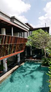 a swimming pool in front of a house with a bridge at The Kemilau Hotel & Villa Canggu Bali in Canggu