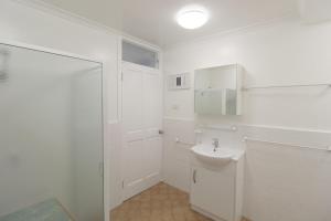 een witte badkamer met een wastafel en een douche bij Beachfront 4, 25 Willow Street in Crescent Head