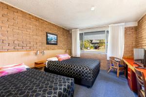 a room with two beds and a brick wall at Aquajet Motel in Coffs Harbour