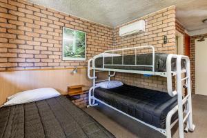 
two bunk beds in a room with a brick wall at Aquajet Motel in Coffs Harbour
