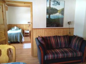 ein Wohnzimmer mit einem Sofa und einem Bett in der Unterkunft Hotelli Möhkön Rajakartano - Ilomantsi in Petkeljärvi