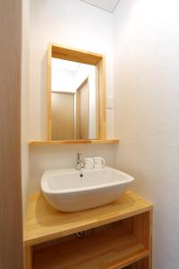 La salle de bains est pourvue d'un lavabo et d'un miroir sur une étagère. dans l'établissement Guest House Keiten, à Kyoto