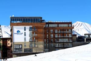 un edificio nella neve con montagne sullo sfondo di Oto' apartmant Gudauri loft a Gudauri