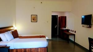 a hotel room with a bed and a television at Abad Green Forest Thekkady in Thekkady