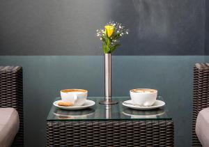 a table with two cups and a vase with flowers at Eka Hotel Nairobi in Nairobi