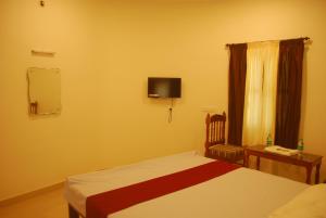 a bedroom with a bed and a tv on the wall at Hotel Jebasakthy in Kanyakumari