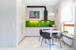 una cocina con mesa, sillas y una pared verde en Apartment Warsaw Smoleńskiego by Renters, en Varsovia