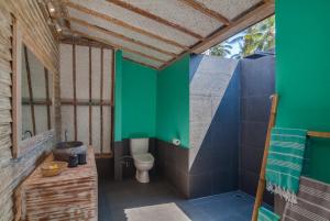 La salle de bains est pourvue de toilettes et d'un mur vert. dans l'établissement Gili Meno Escape - Adults Only, à Gili Meno