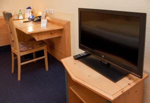 TV de pantalla plana en la parte superior de un escritorio de madera en Hotel Waldeck Garni, en Kist