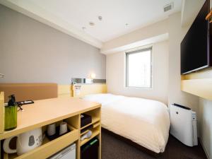 una piccola camera da letto con un letto e una scrivania di Super Hotel Tokyo Shiba a Tokyo
