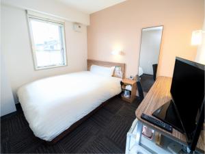 a hotel room with a bed and a television at Super Hotel Hirosaki in Hirosaki