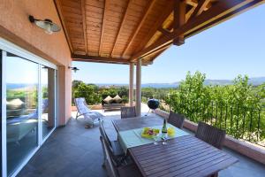 a wooden table on a patio with a view at Valinco Locations OLMETO PLAGE in Olmeto