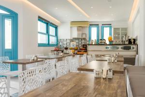 a dining room with wooden tables and white chairs at Nikolas Hotel in Karterados