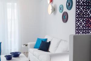 a white living room with a white couch and clocks on the wall at Villa Del Sol Mykonos in Ornos