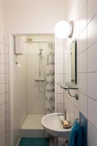 La salle de bains blanche est pourvue d'une douche et d'un lavabo. dans l'établissement Apartment in der Yogaschule, à Cologne