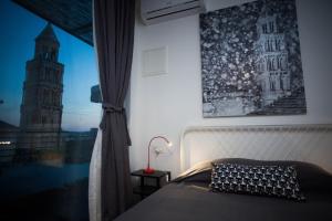 ein Schlafzimmer mit einem Bett und einem Fenster mit einem Uhrturm in der Unterkunft Studiolo Belvedere in Split