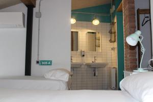a room with two beds and a bathroom with a sink at Green River Hostel in Cuenca