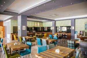 Un restaurante con mesas de madera y sillas azules. en leto city hotel, en Eskisehir