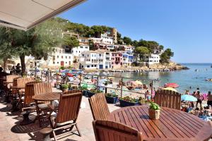 eine Terrasse mit Tischen und Stühlen und ein Strand in der Unterkunft Hostal Sa Tuna in Begur