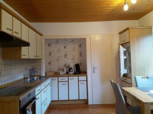 a kitchen with white cabinets and a sink and a table at Grüne Oase in Hargesheim +5 photos
