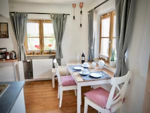 uma sala de jantar com mesa, cadeiras e janelas em Ferienwohnung Heimat em Grassau