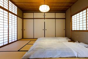 a bedroom with a large bed in a room with windows at Konuka Yakushi Temple House in Kyoto