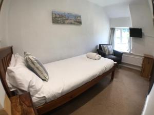 a small bedroom with a bed and a chair at The White Horse Inn in Washford